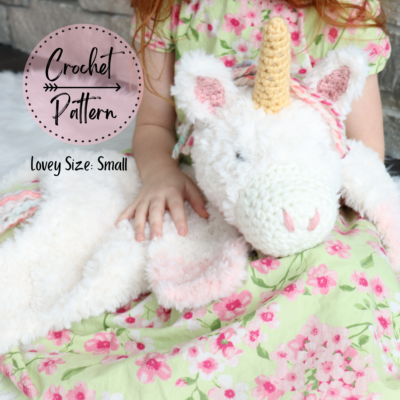 small crochet unicorn lovey laying on girl