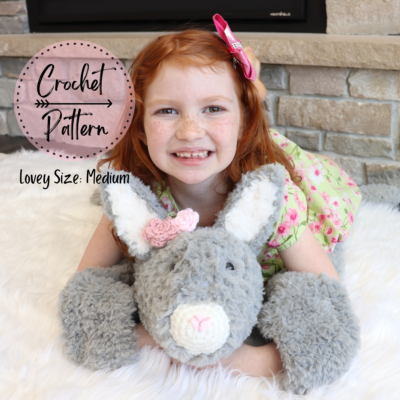 Girl laying on medium crochet bunny lovey.