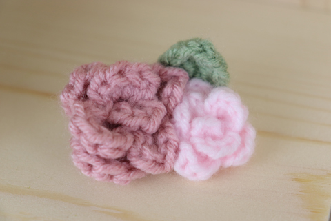 One larger pink crochet rose with a smaller light pink crochet rose