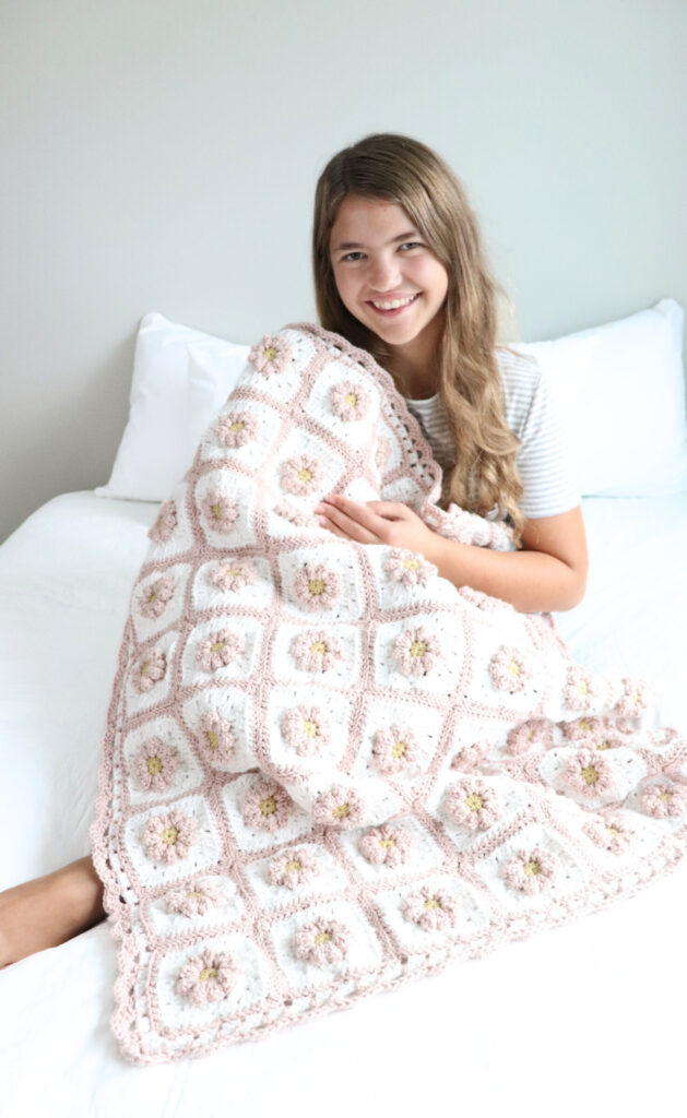 picture of Emily (owner of Sweet Creek Patterns) with her Granny Square blanket